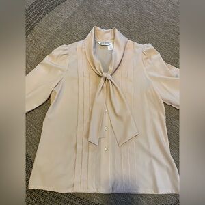 vintage-style tan-colored blouse w/ a pleated front, tie neck, & long sleeves.